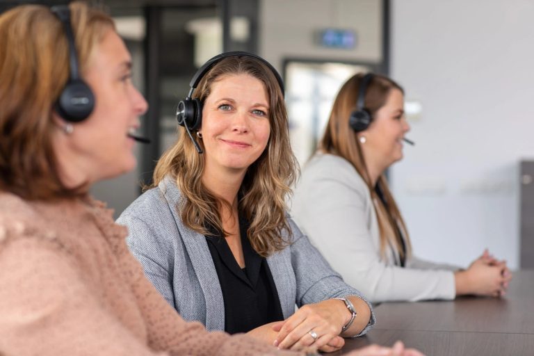 portofoons huren bij flash verhuurservice, een vrolijke dame die de klant telefonisch te woord staat met een headset op. Een portofoon huur je bij Flash
